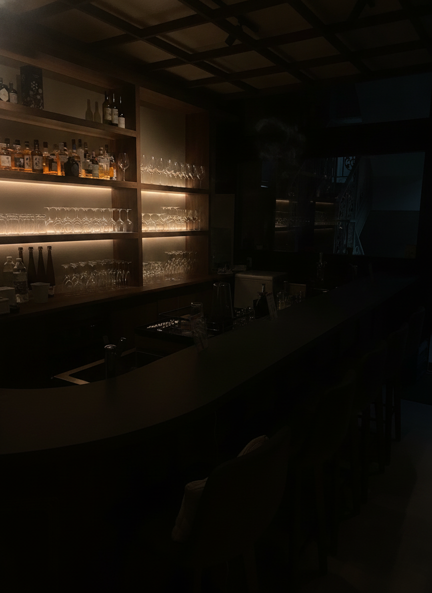 Backlit glassware on dark walnut shelves behind a bare stone counter, under a coffered wooden-lattice ceiling